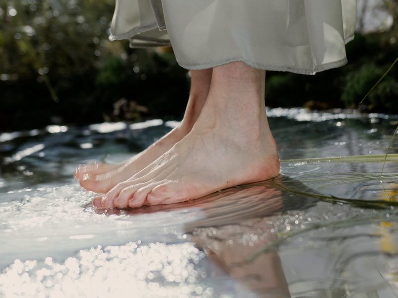 Bare feet standing in clear shallow water