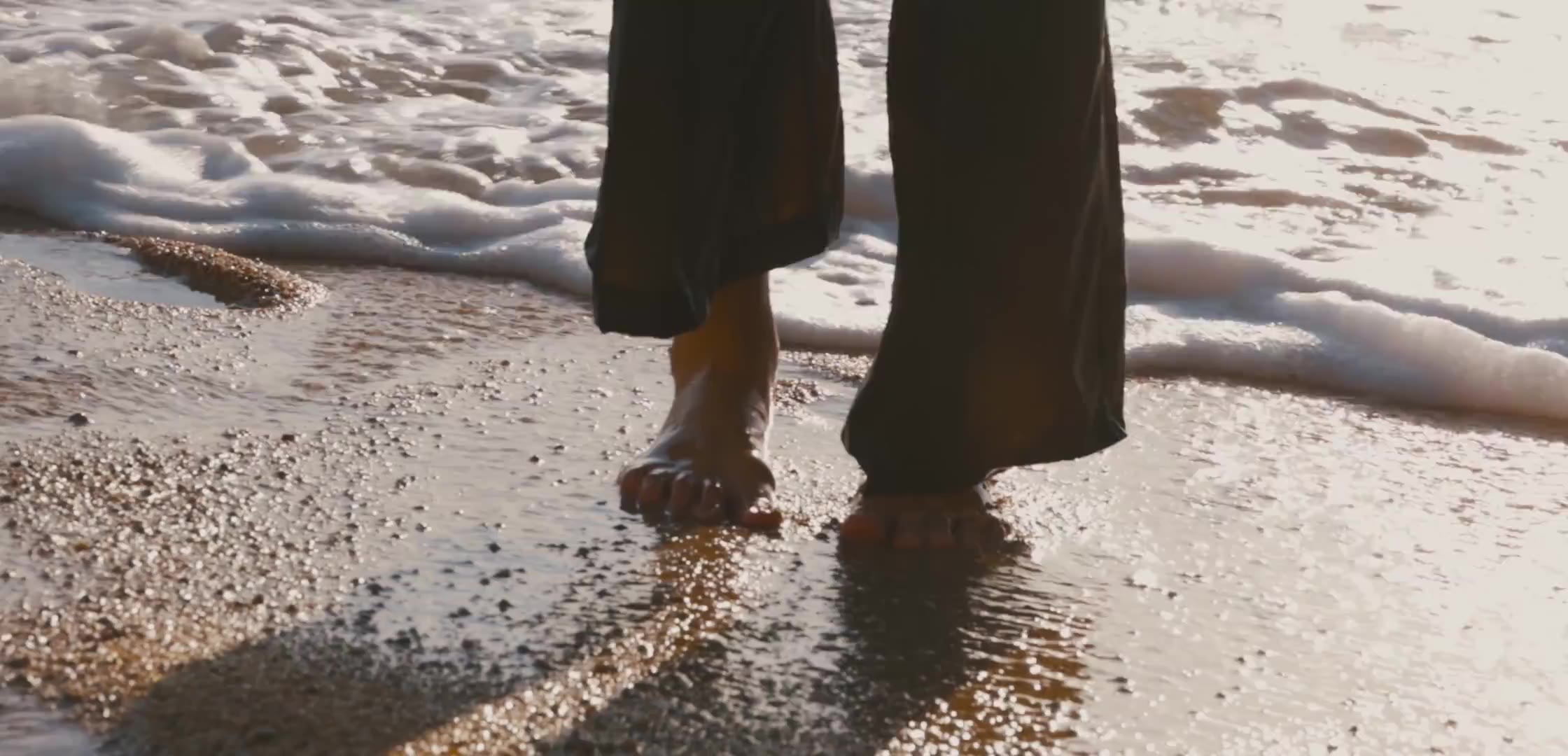 Feet at the edge of ocean water at sunset