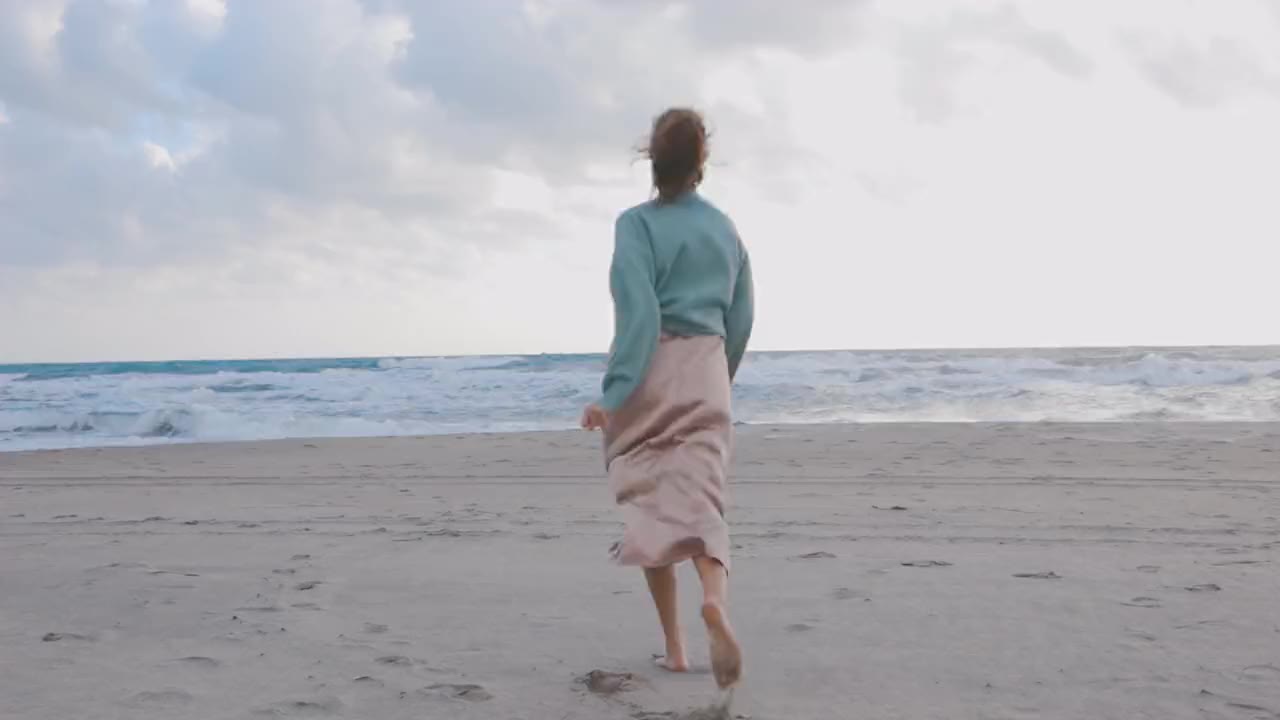 A person walking alone on a quiet shoreline in soft pale light